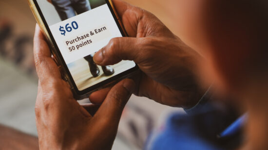 Customer loyalty program concept in e-commerce for customer engagement. Man holding phone displaying earning points after purchasing online.